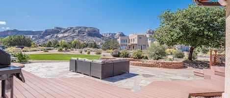 Un patio con suelo de piedra, mobiliario exterior y vistas a un paisaje montañoso.