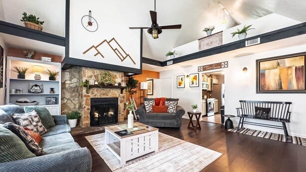 Un salón amplio con chimenea, ventilador de techo y un cuadro grande en la pared.