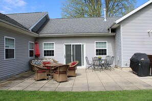 A patio with wicker furniture, a grill, and a sliding glass door. - Charming 3-bedroom house: Winona Lake Front (Warsaw)