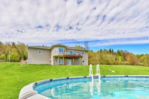 Ein zweistöckiges Haus mit Swimmingpool, überdachter Terrasse und Rasengarten.