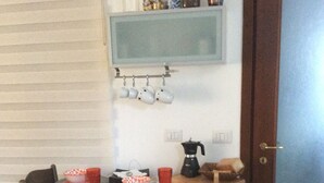 A dining area with a table set for two, a coffee maker, and a shelf above the table with jars and mugs. - Cómodo Malpensa/Como/Milan train connection, A9 exit 14m Switzerland.  (Fino Mornasco)