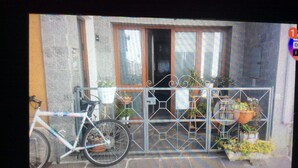 A bicycle parked in front of a building with a metal gate and potted plants. - Cómodo Malpensa/Como/Milan train connection, A9 exit 14m Switzerland.  (Fino Mornasco)