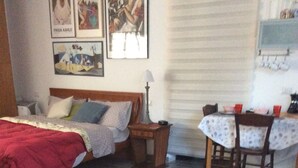 A room with a bed, a table with a placemat, and a dining area with chairs and a table. - Cómodo Malpensa/Como/Milan train connection, A9 exit 14m Switzerland.  (Fino Mornasco)