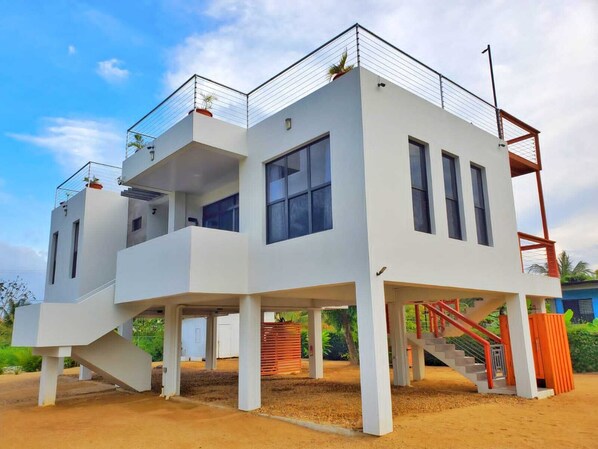 A modern multi-story house with a flat roof, large windows, and a staircase leading to the upper floor. - Modern Hopkins Home: Beach & Village Access (Hopkins)