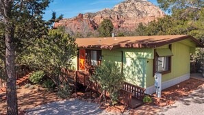 A small, single-story building with a green exterior and a brown roof, surrounded by trees and a mountainous backdrop. - The Tourist & Hiking Spot!

 (Sedona)