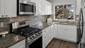 A modern kitchen with white cabinets, a stainless steel microwave, a gas stove, and a refrigerator. - The Tourist & Hiking Spot!

 (Sedona)