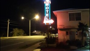 A motel with a neon sign, a single-story building, and a visible entrance.