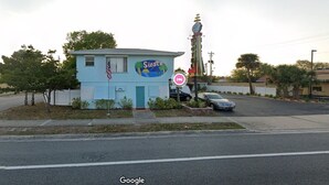 A small, light blue building with a sign reading "Siesta Motel" and an American flag.