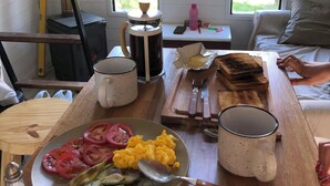 Een ontbijttafel met eten, een koffiezetapparaat en een raam met uitzicht op bomen.