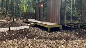 Una cabaña de madera con terraza, rodeada de un bosque.