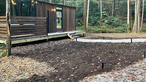 Una cabaña de madera con terraza, rodeada de un bosque.
