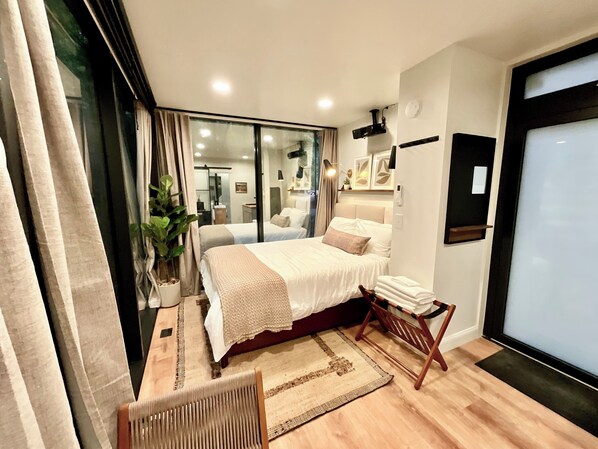 Un dormitorio moderno con una cama grande, una zona de descanso pequeña y vistas a través de un ventanal.
