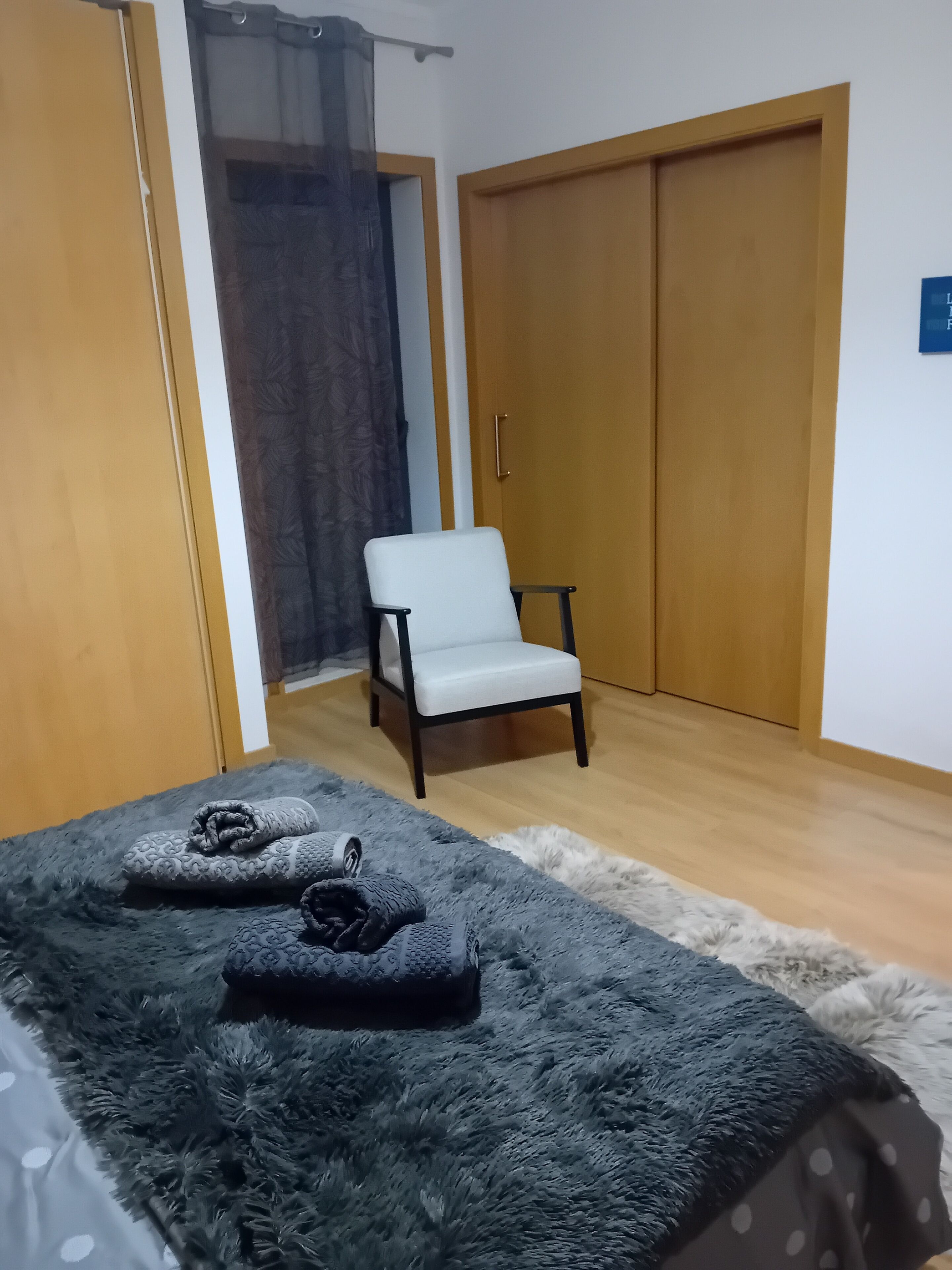Un dormitorio con cama, una silla y un armario.