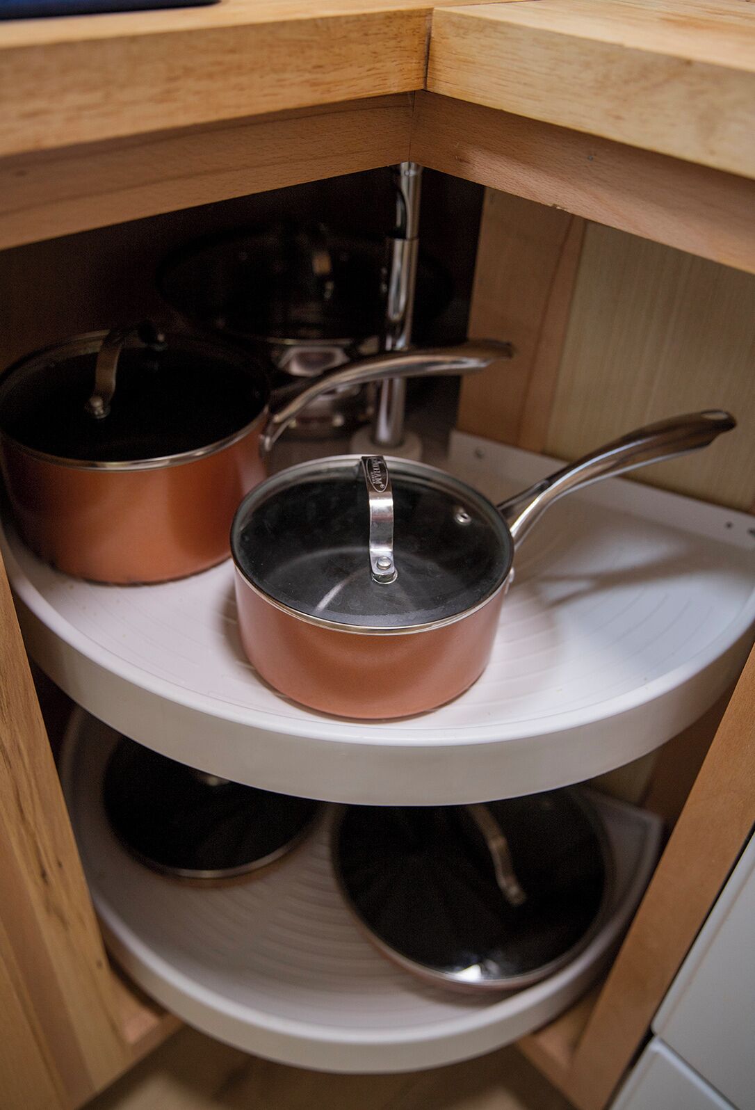 Een keuken met koperen pannen op een witte plank.
