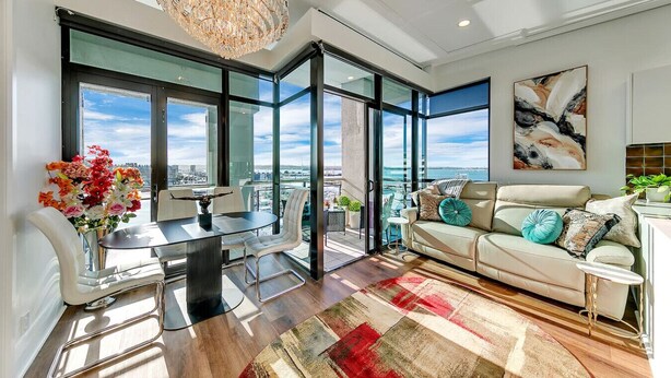 A modern living room with a dining area, large windows, a chandelier, and a city view. - Penthouse Crown Jewel (Auckland)