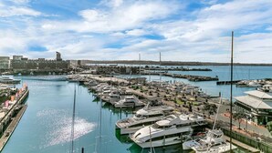 A marina with boats docked, a bridge in the background, and buildings along the waterfront. - Penthouse Crown Jewel (Auckland)