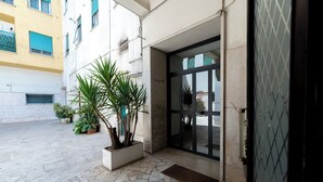 A building entrance with a stone-paved courtyard, potted plants, and a glass door. - Near Vatican Guest House Irnerio47 (Rome)