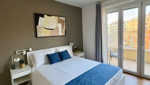A modern hotel room with a large bed, a nightstand, a bedside table, a wall-mounted artwork, and a view of the city through the window. - Near Vatican Guest House Irnerio47 (Rome)