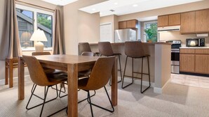 Une cuisine moderne avec des meubles en bois, un îlot central et un coin repas comprenant une table et des chaises.