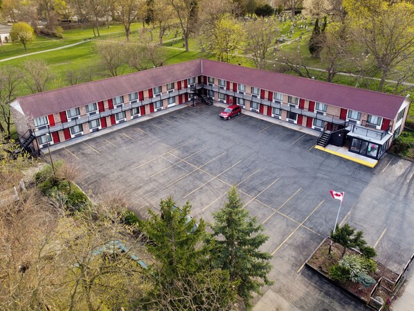 Un edificio de varios pisos con techo rojo, un estacionamiento y una bandera.