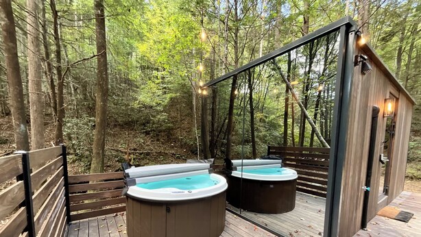 Une terrasse en bois dotée de deux bains à remous et d’une structure entièrement vitrée.