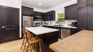 A modern kitchen with dark cabinets, stainless steel appliances, and a central island with bar stools.