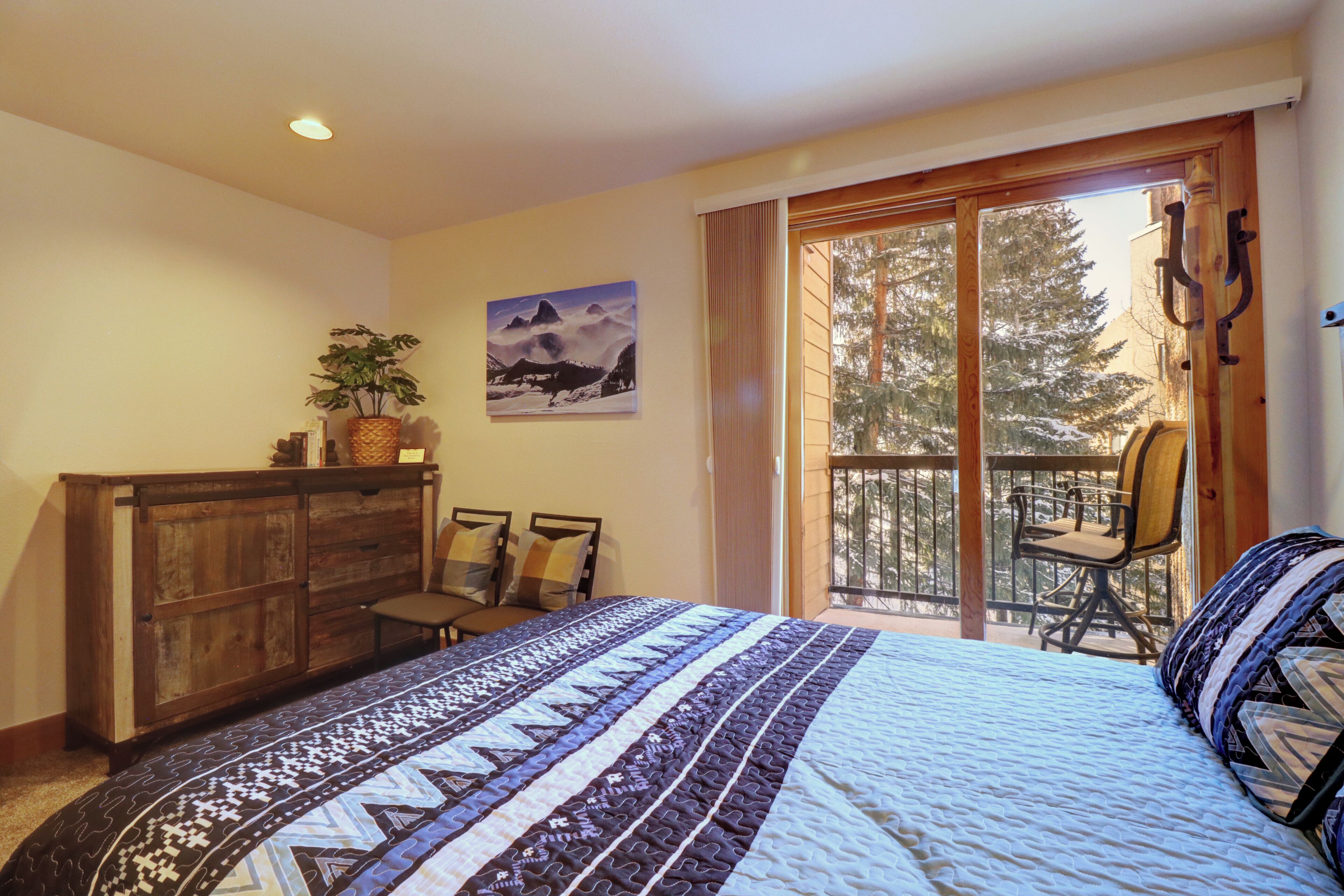 Ein Schlafzimmer mit einem großen Bett, einer Holzkommode, einem Stuhl und einem Balkon mit Sitzgelegenheit.
