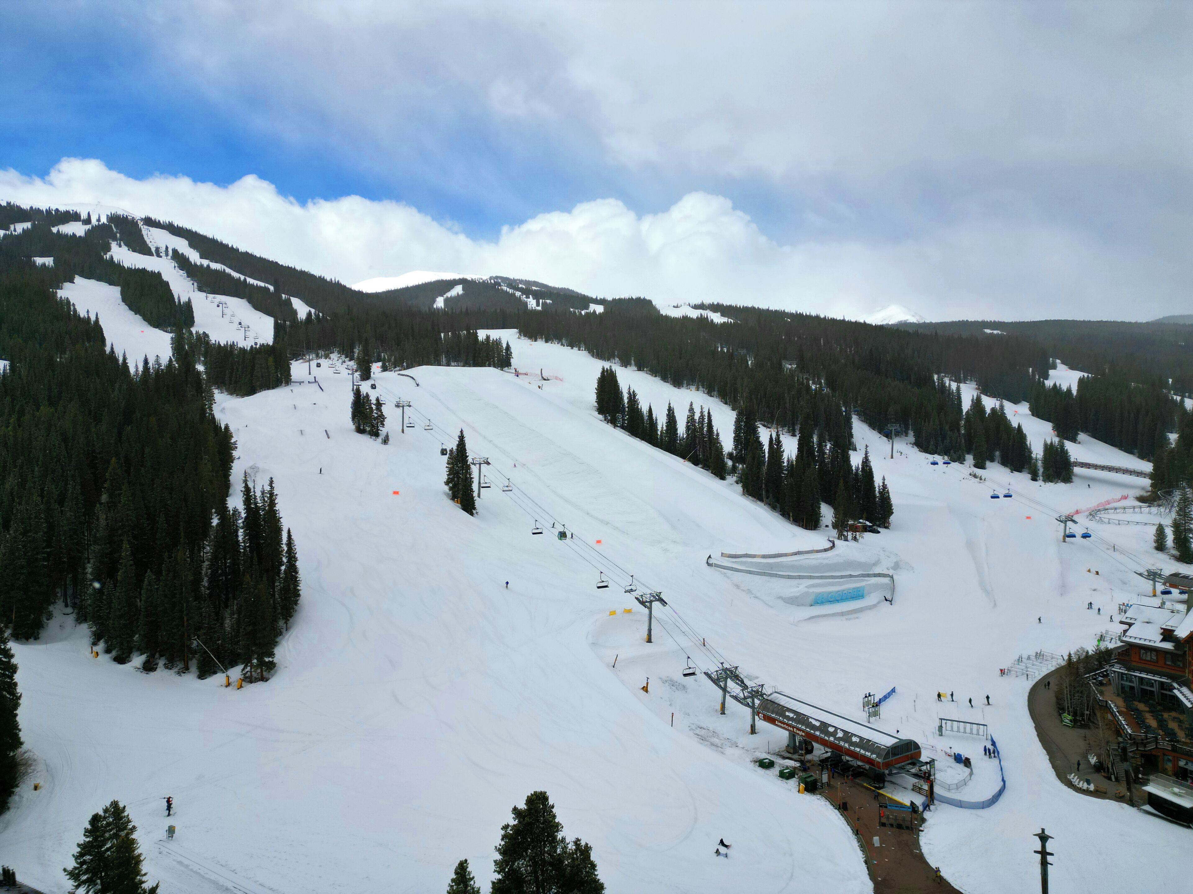 A ski resort with a ski lift, snow-covered slopes, and a building with a ski lift.