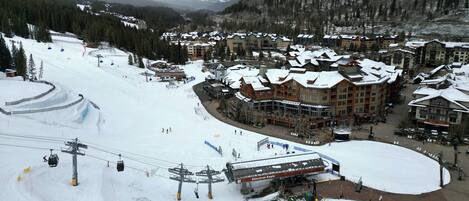 Een ski-resort met een skilift, gebouwen met sneeuw bedekte daken en een bergachtige achtergrond.