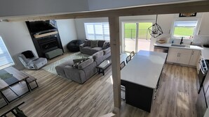 Un grand espace de vie comprenant un canapé, une table à manger et un coin cuisine avec un plan de travail et des placards.