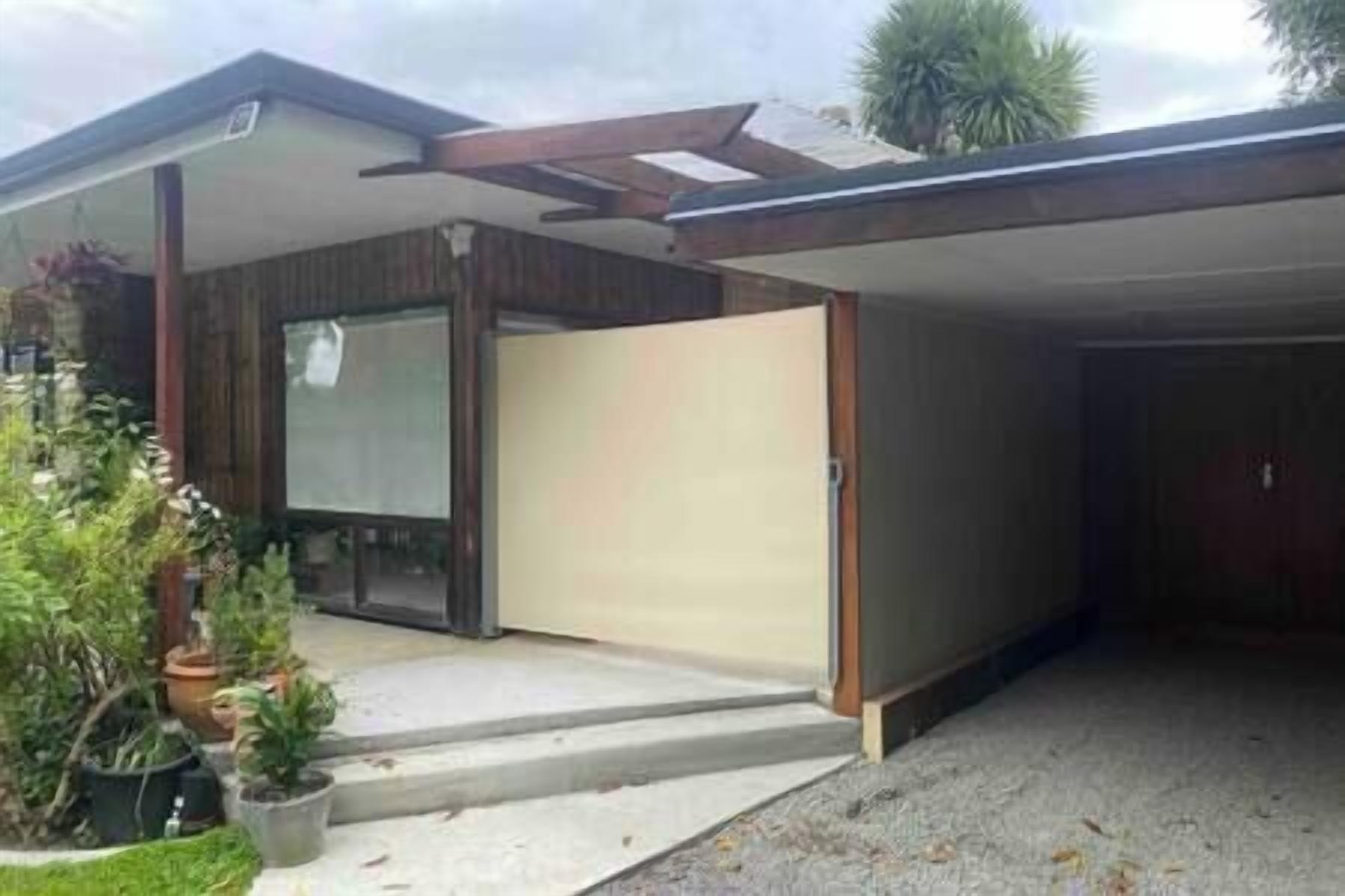 Ein modernes Haus mit Garage, überdachter Veranda und kleinem Garten.