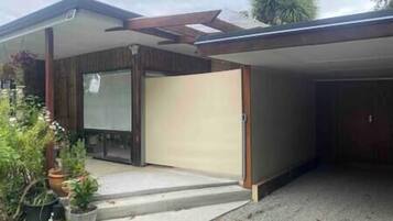 Une maison moderne dotée d’une porte de garage, d’un porche couvert et d’un petit jardin.