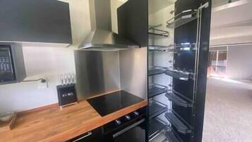 Una cocina moderna con encimera de madera, electrodomésticos de acero inoxidable y horno negro.