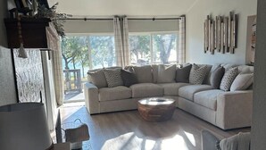 Una sala moderna con un sofá modular, una mesa de centro redonda y un ventilador de techo.