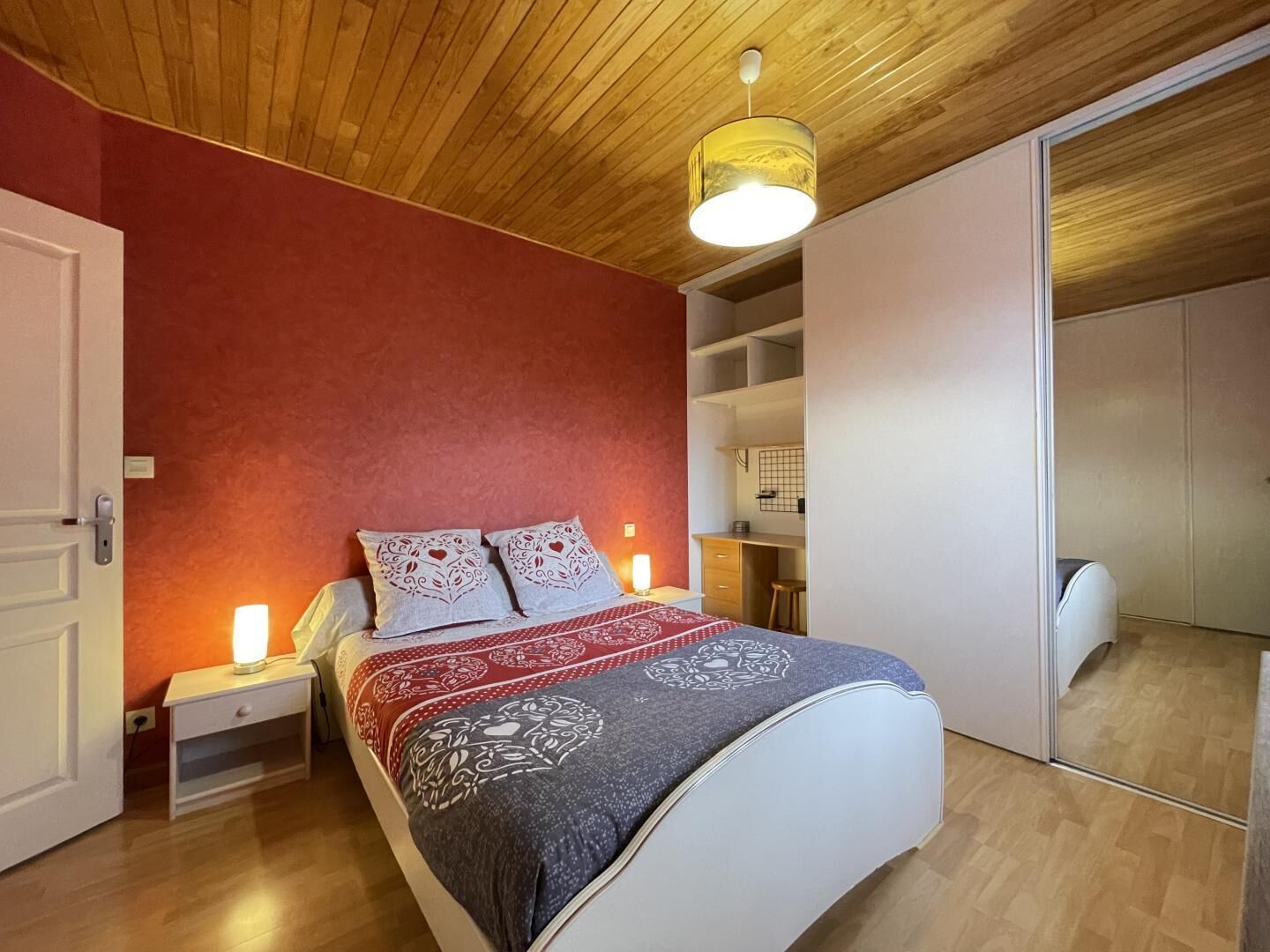 A bedroom with a bed, bedside tables, a wardrobe, and a ceiling light fixture.