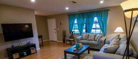 A living room with a flat-screen TV, two sofas, a coffee table, and a lamp.