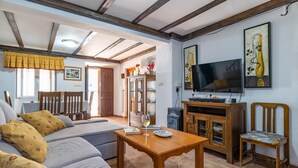 A living room with a sofa, a wooden table, a TV, and a cabinet. - Amazing home in Setenil de las Bodegas (Setenil de las Bodegas)