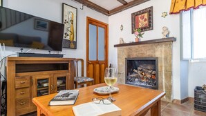 A cozy living room with a fireplace, wooden furniture, a television, and a book. - Amazing home in Setenil de las Bodegas (Setenil de las Bodegas)