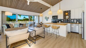 A modern kitchen with a wooden ceiling, bar stools, a dining area with a table and chairs, and a view of the outdoors. - NEW!! Charming 1 bedroom bungalow in amazing Kailua-Kona Sept specials inquire!! (Kailua-Kona)