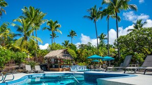 A pool area with lounge chairs, a thatched-roof structure, and palm trees. - NEW!! Charming 1 bedroom bungalow in amazing Kailua-Kona Sept specials inquire!! (Kailua-Kona)