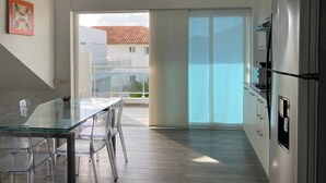 A modern kitchen with a glass dining table, stainless steel appliances, and a view to a balcony. - Baya Azul Bayahibe - Penthouse 401 (San Rafael del Yuma)