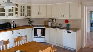 Une cuisine avec des meubles blancs, une table en bois et un fourneau.