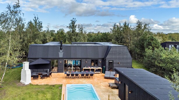 Una casa moderna con piscina, mobiliario de exterior y una terraza amplia.