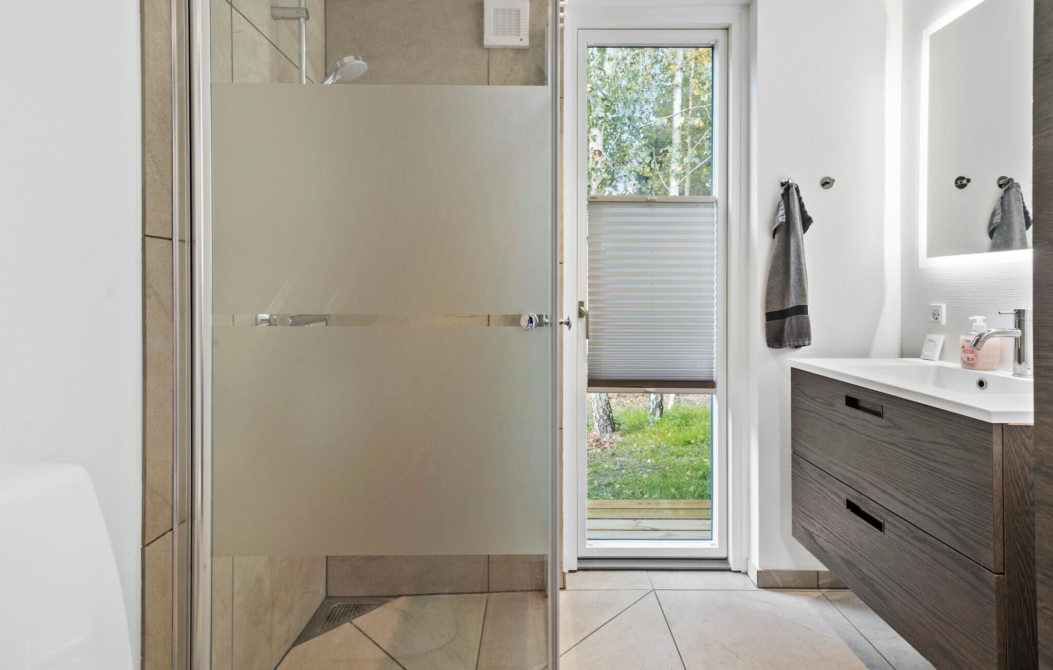 A modern bathroom with a shower, a toilet, and a sink with a mirror.
