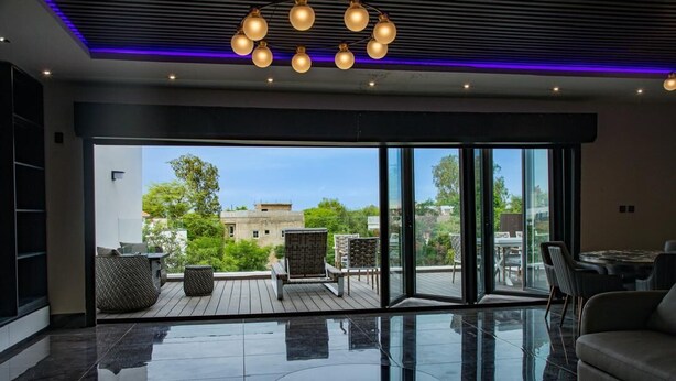 A modern living room with a glass coffee table, a sofa, and a dining area with chairs. - Luxury seaside villa (Ngaparou)