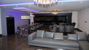A modern living room with a marble coffee table, grey sofa, and a bar area with seating. - Luxury seaside villa (Ngaparou)
