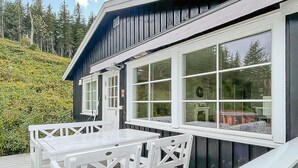 A wooden cabin with a deck, large windows, and a view of a forested hillside. - 4 bedroom cozy home in Bø i Telemark (Bø i Telemark)