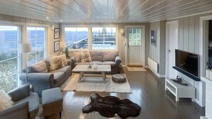 A spacious living room with a large window, a sofa set, a coffee table, a television, and a fur rug. - 4 bedroom cozy home in Bø i Telemark (Bø i Telemark)