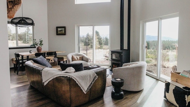 Ein geräumiges Wohnzimmer mit einer großen Couch, einem Kamin und Blick ins Freie.