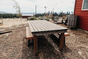 Una mesa de madera rústica con bancos en un patio trasero.